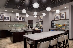 Una cocina moderna con una isla central, taburetes de bar y una larga mesa de comedor.