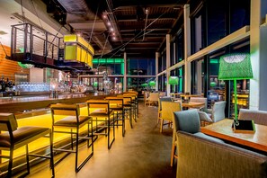 A bar area with seating and a bar counter, large windows, and a high ceiling with exposed beams. - Hilton St. Louis at the Ballpark (St. Louis)