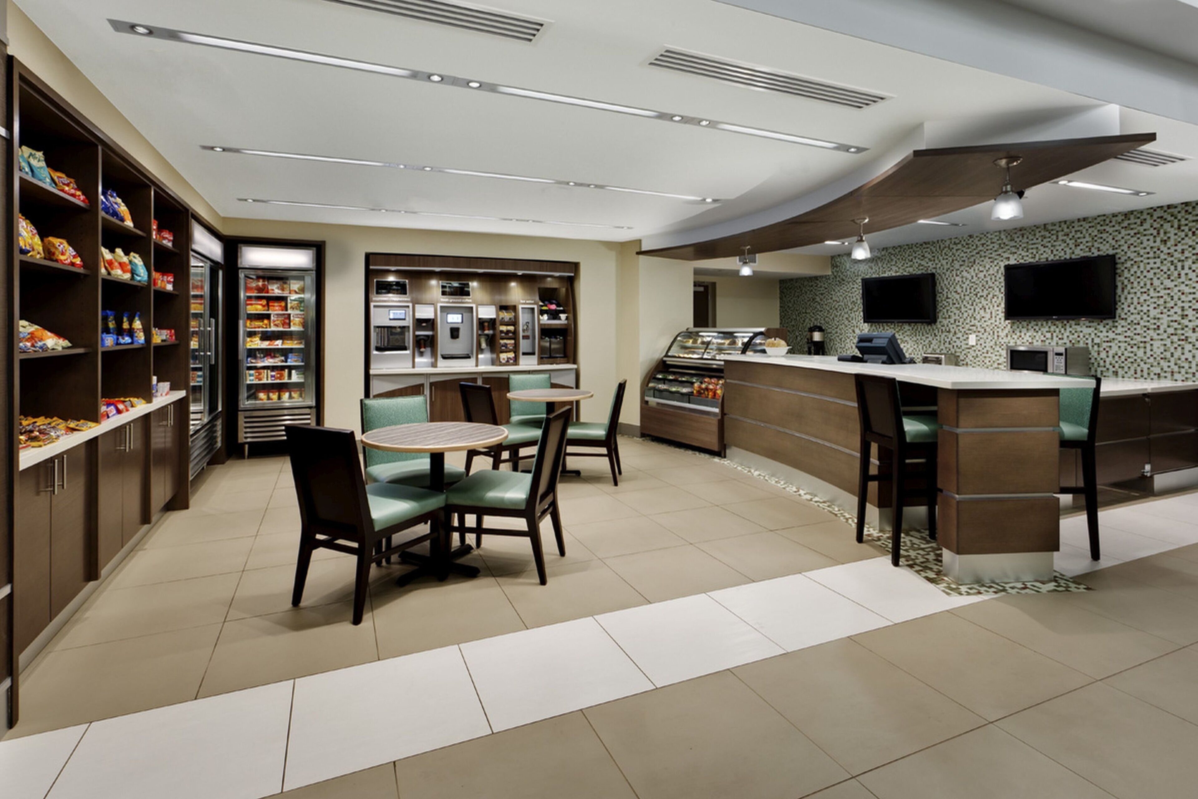 A modern cafe with a counter, seating area, and a variety of food and beverage dispensers.