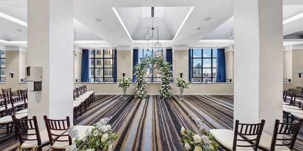 A spacious hall with a patterned carpet, rows of wooden chairs, and a central floral arrangement. - Holiday Inn San Antonio - Riverwalk by IHG (San Antonio)