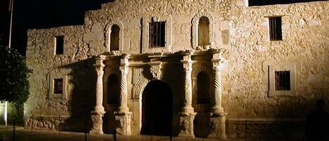 A historic building with a large archway, columns, and a stone facade at night.