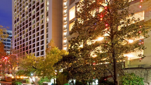 Un hotel de gran altura con varios pisos, balcones y un letrero verde llamativo.