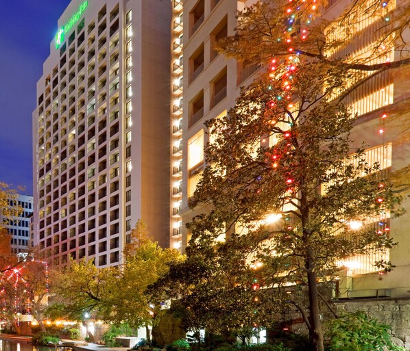 A high-rise hotel with multiple floors, balconies, and a prominent green sign. - Holiday Inn San Antonio - Riverwalk by IHG (San Antonio)
