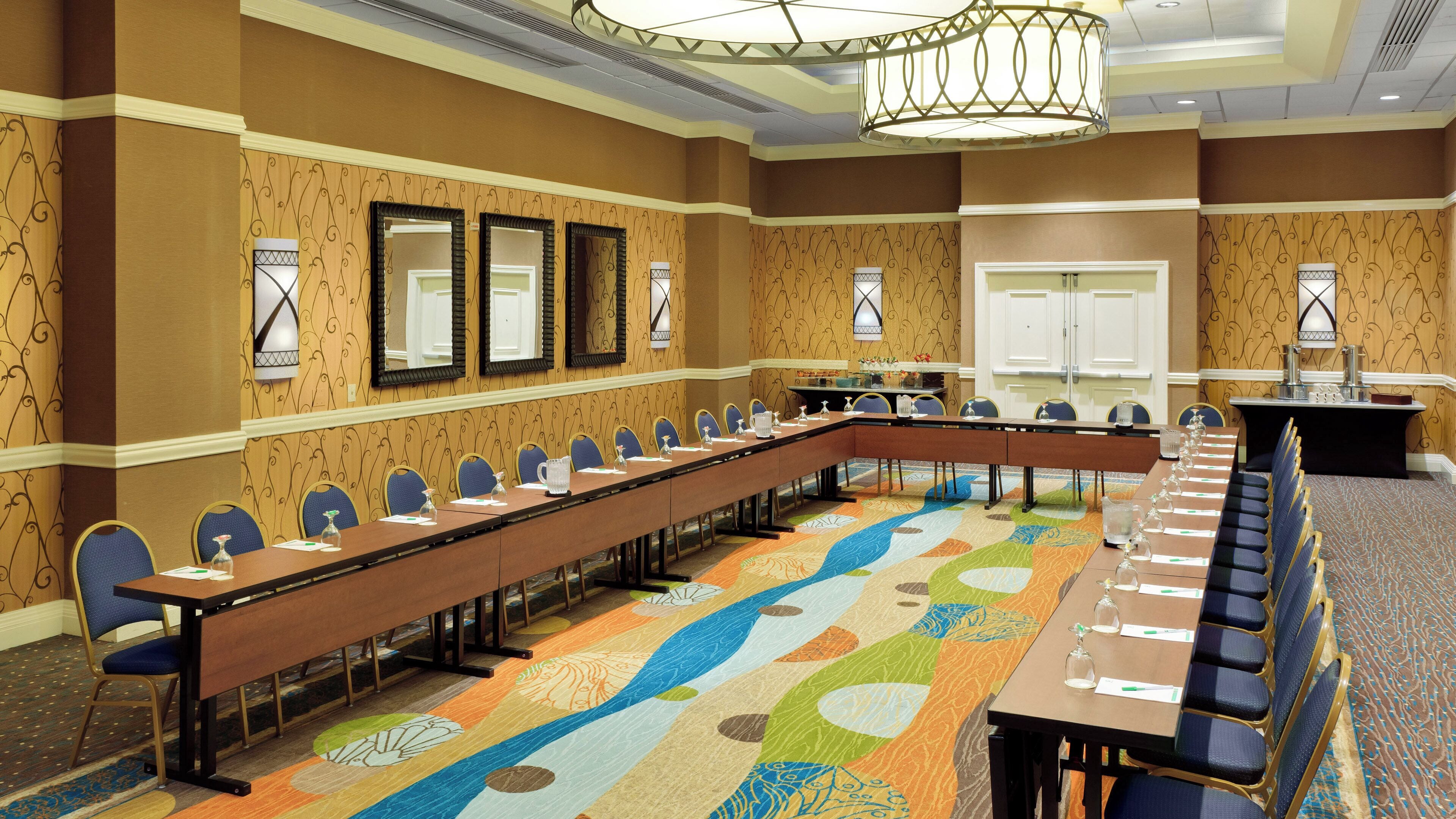 Une salle de conférence avec une longue table, des chaises et un tapis à motifs.