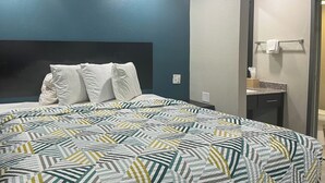 Une chambre d’hôtel avec un lit, une table de chevet, un miroir et un porte-serviettes.