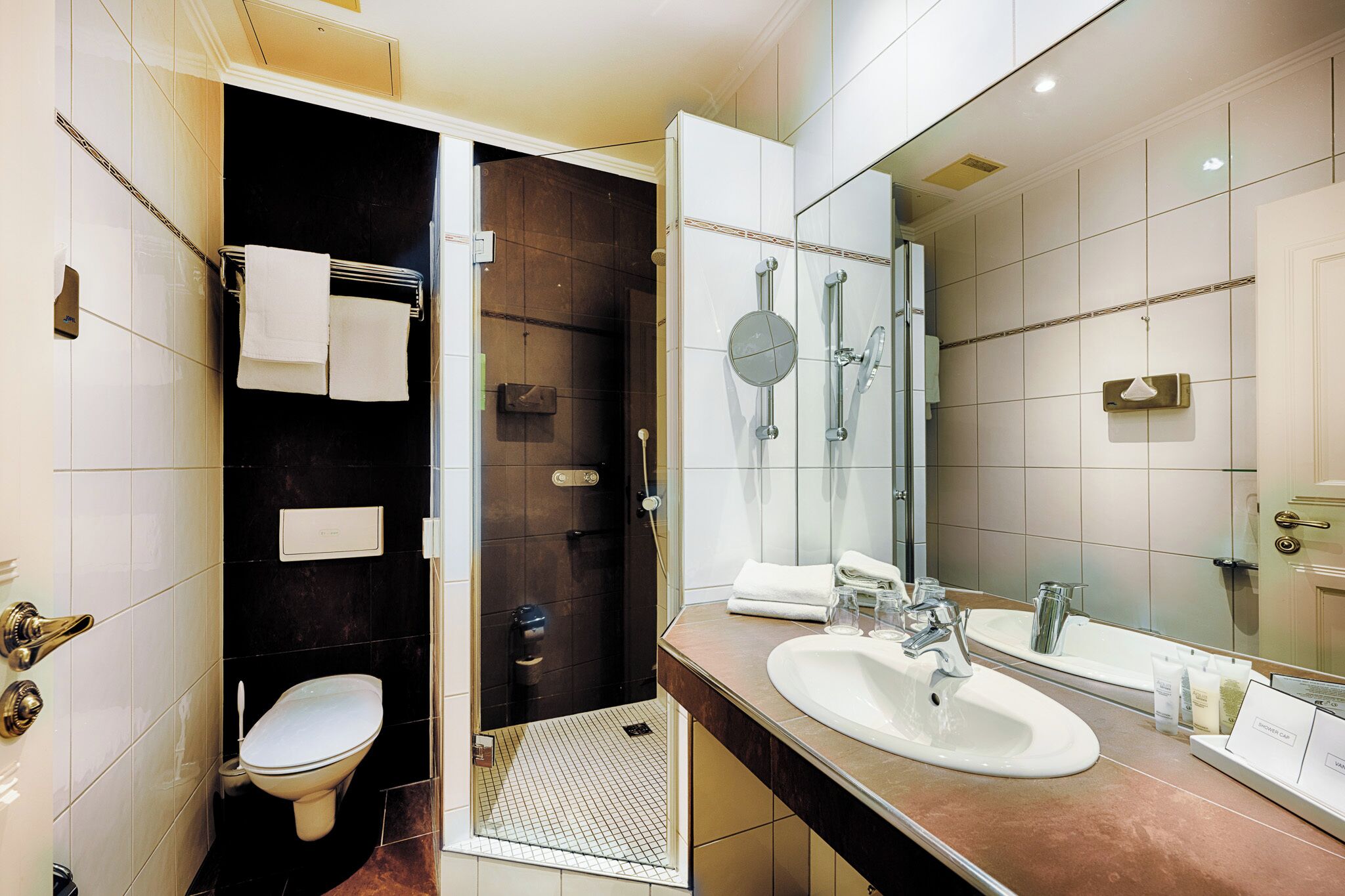 Une salle de bain moderne avec des toilettes, un bidet et un grand miroir.