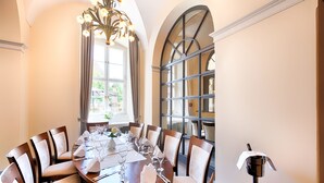 Een eetkamer met een ronde tafel, gedekt voor zes personen, omringd door gestoffeerde stoelen.