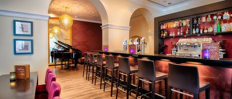 A bar area with a piano, wooden flooring, and bar stools.