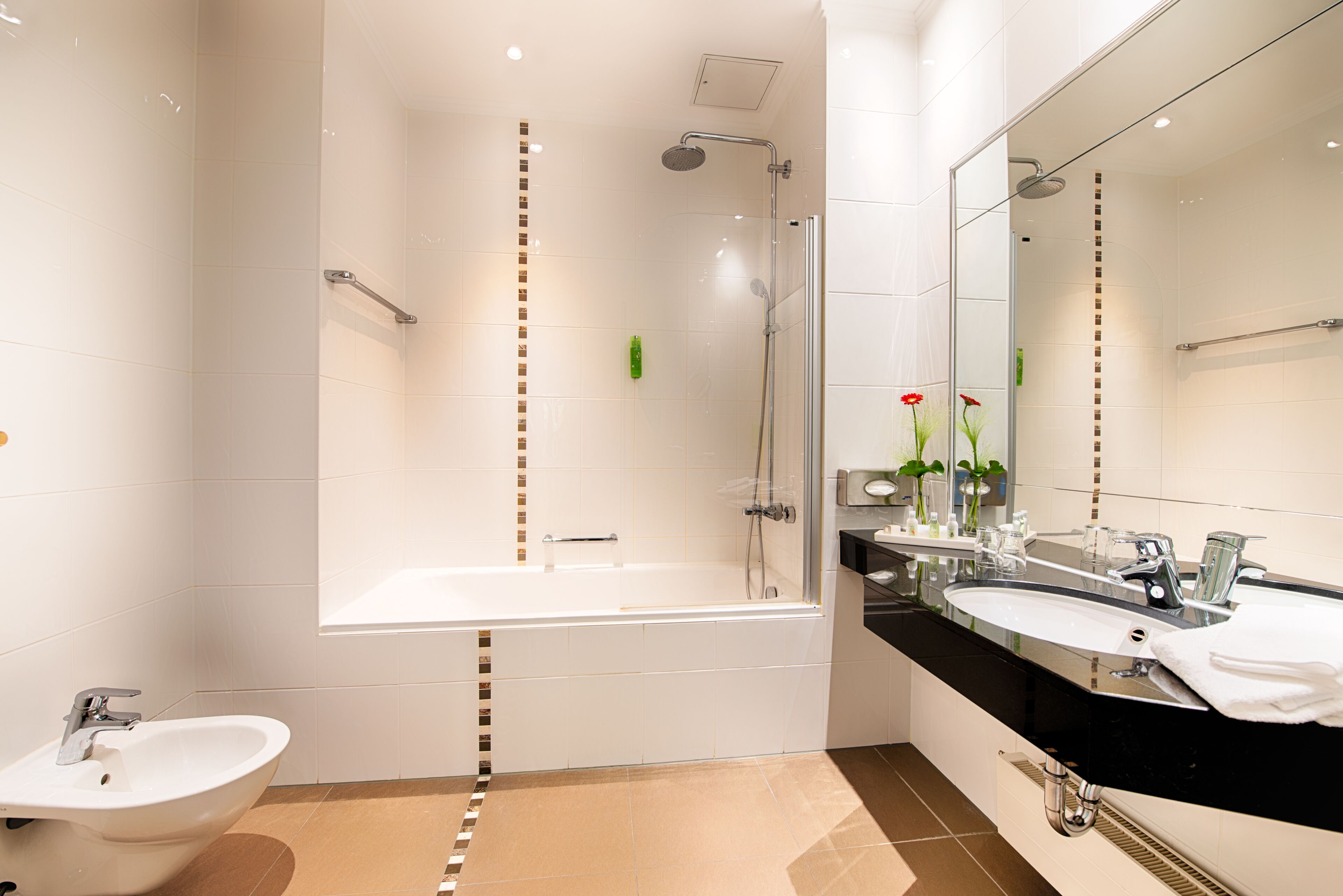 Ein modernes Badezimmer mit einer gläsernen Dusche, einer freistehenden Badewanne, einem Doppelwaschtisch und einem Standwaschbecken.