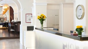 Een receptiegedeelte met een modern design, met een receptiebalie, een klok en een vaas met zonnebloemen.