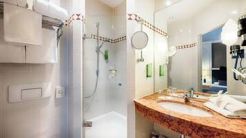 A modern bathroom with a walk-in shower, a double sink vanity, and a large mirror.