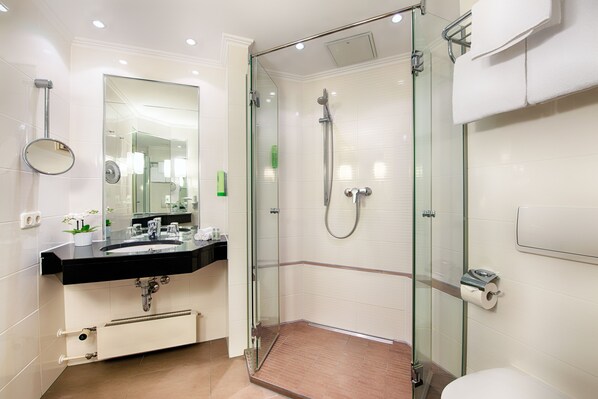 A modern bathroom with a glass-enclosed shower, a black sink, and a white toilet.