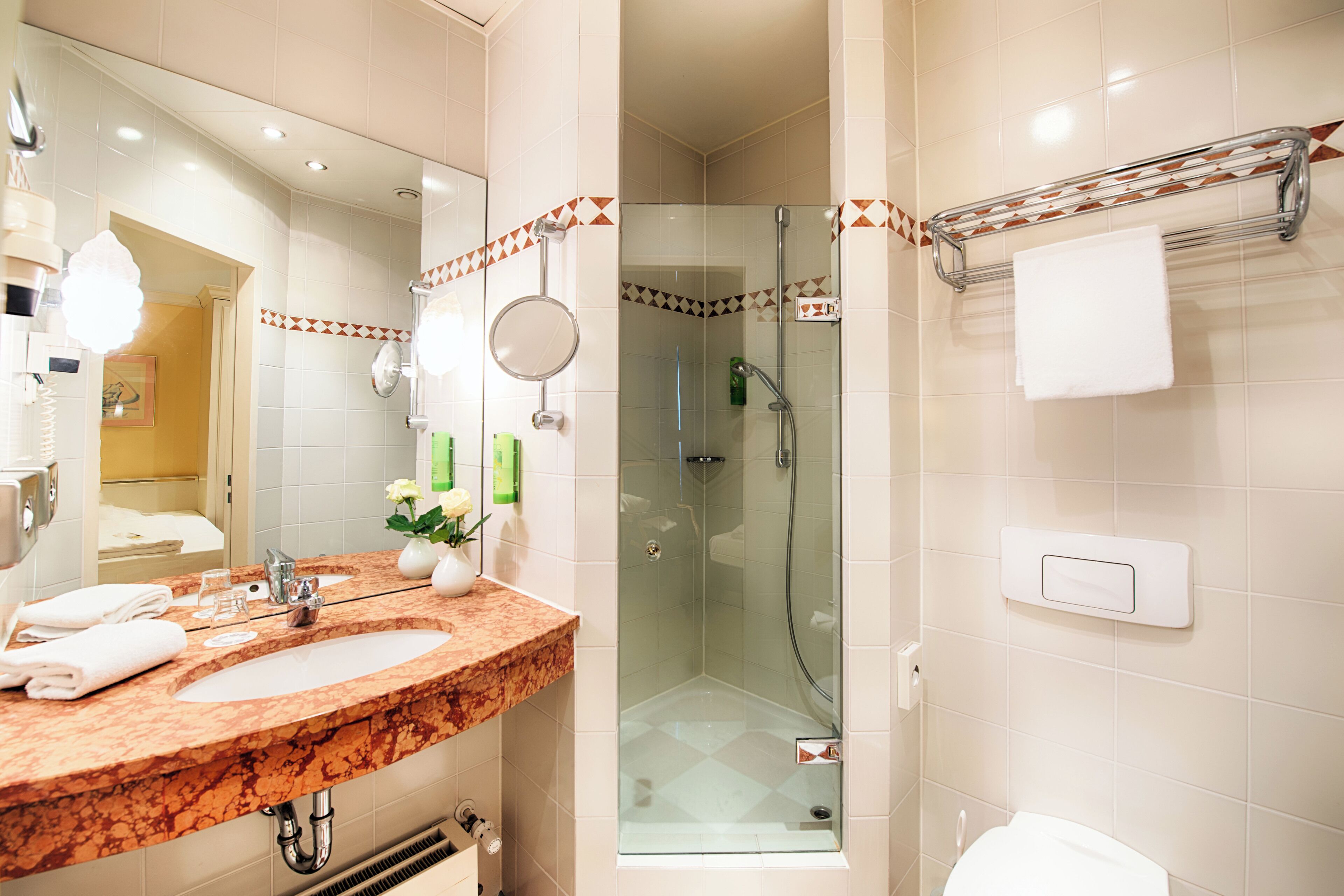 A modern bathroom with a marble sink, a glass-enclosed shower, and a towel rack.
