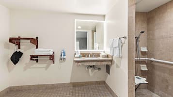 A bathroom with a sink, mirror, towel rack, shower, and a tiled floor.