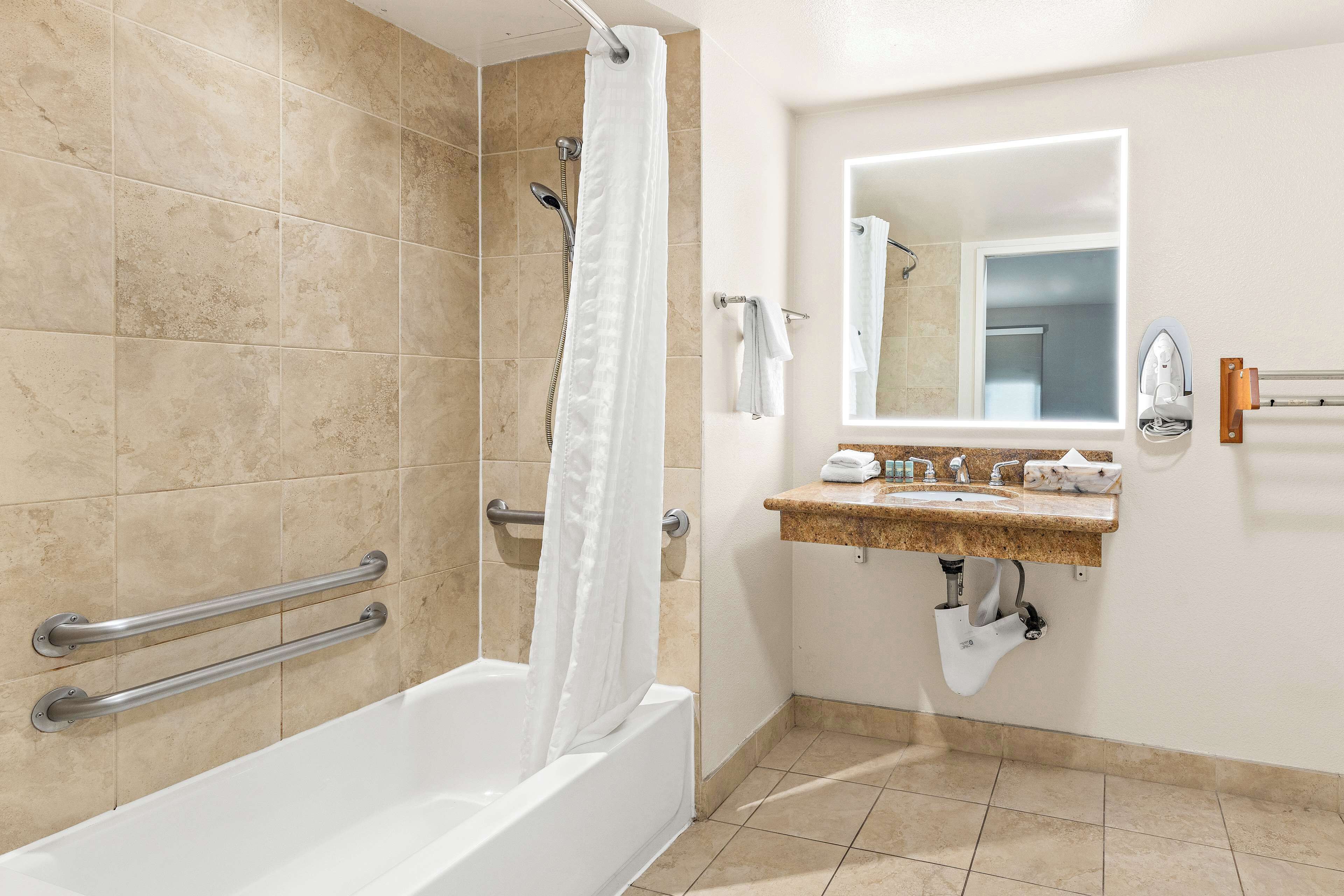 A bathroom with a bathtub, a shower, a vanity with a mirror, and a towel rack.