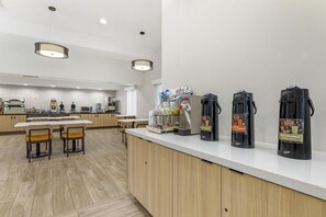 A modern kitchen area with a white countertop, coffee machines, and a seating area with wooden chairs. - Best Western Chula Vista/Otay Valley Hotel (Chula Vista)