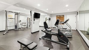 A modern gym with cardio equipment, weight machines, and a television.