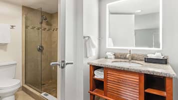 A bathroom with a glass-enclosed shower, a sink with a mirror, and a toilet.