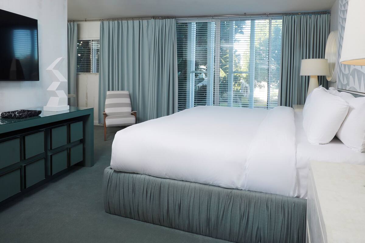 Una habitación de hotel con una cama grande, un escritorio, una silla y un televisor.