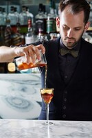 Un camarero sirviendo una bebida en una copa de martini.