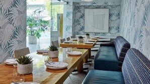 A modern dining area with a wooden table set for four, surrounded by chairs. There are potted plants on the table, and a large abstract painting on the wall. - Avalon Hotel Beverly Hills, a Member of Design Hotels (Beverly Hills)