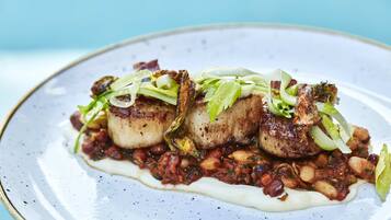 A plate of food with seared scallops, beans, and greens.