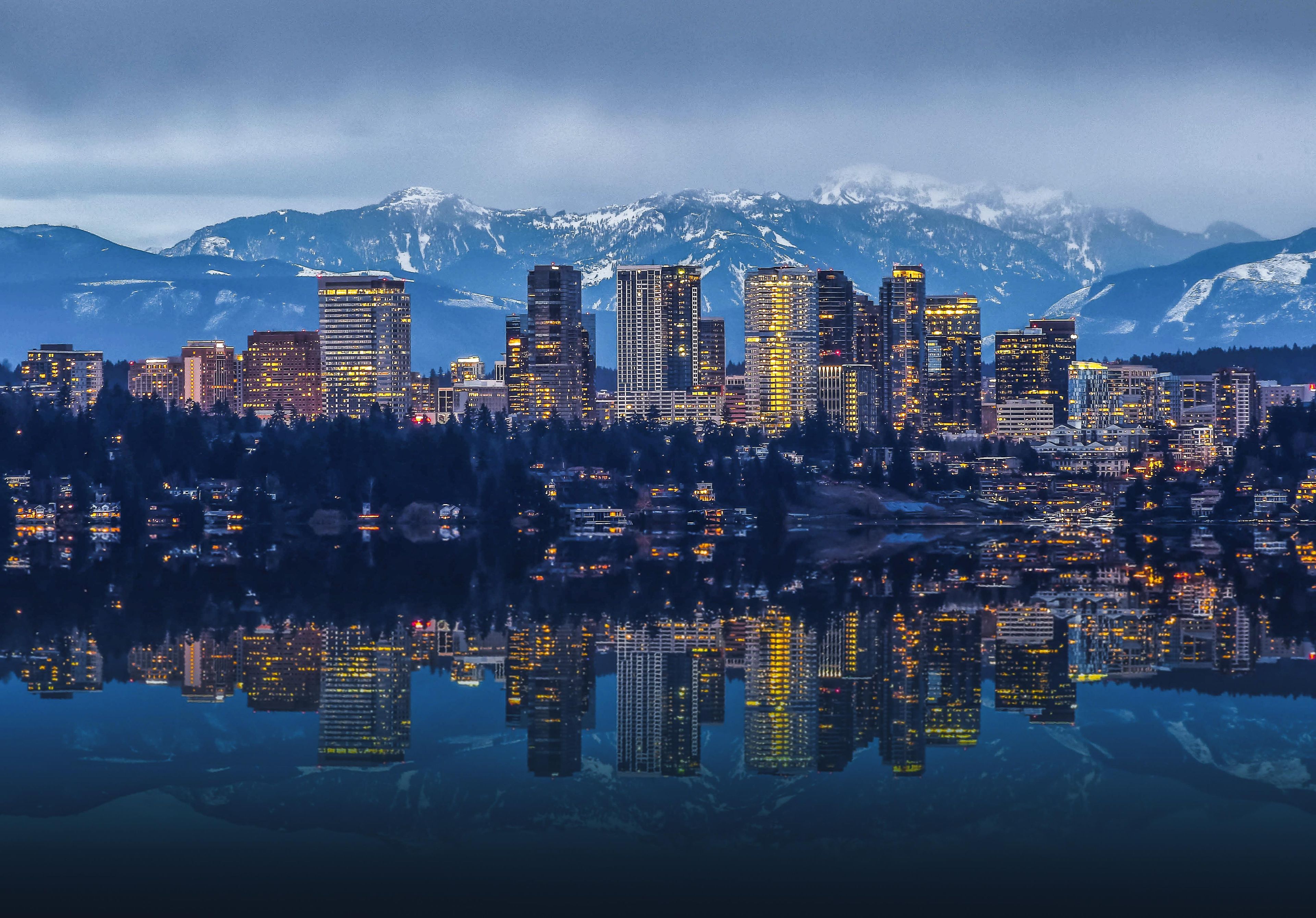 A city skyline with high-rise buildings and a mountain range in the background.