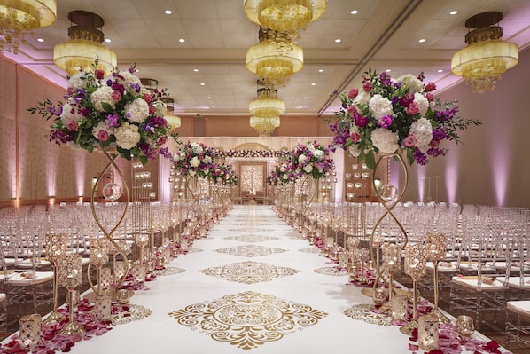 Formal events take place in this grand banquet hall with a long table, ornate chandeliers, and elegant floral arrangements.