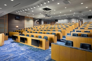 A conference room with tiered seating, built-in screens, and a carpeted floor. - Hyatt Regency Bellevue (Bellevue)
