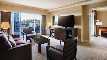 A hotel room with a sofa, a coffee table, a TV, a desk, and a chair.