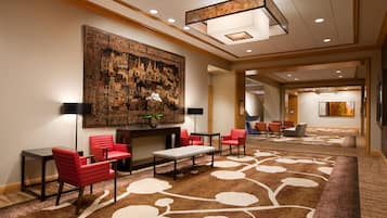 A hotel lobby with a large traditional mural, multiple seating areas, and a carpet with a floral pattern.