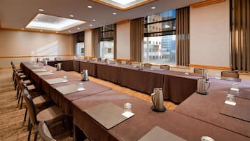 A conference room with a long table, chairs, and a city view through large windows.