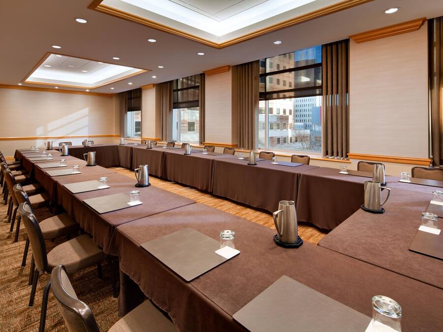 A conference room with a long table, chairs, and a city view through large windows.