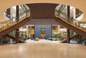 A spacious lobby with a central atrium, two staircases, and a variety of seating areas.