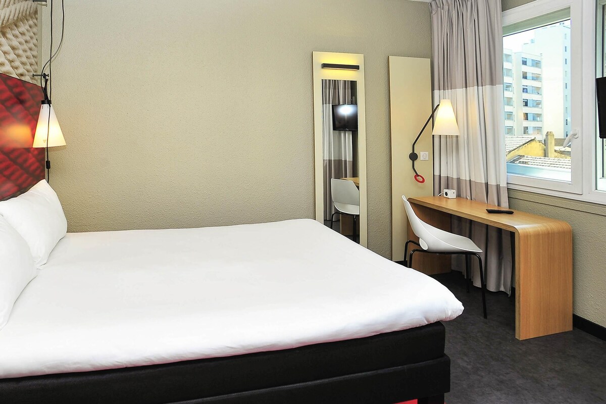 Een hotelkamer met een bed, bureau, stoel en een televisie.