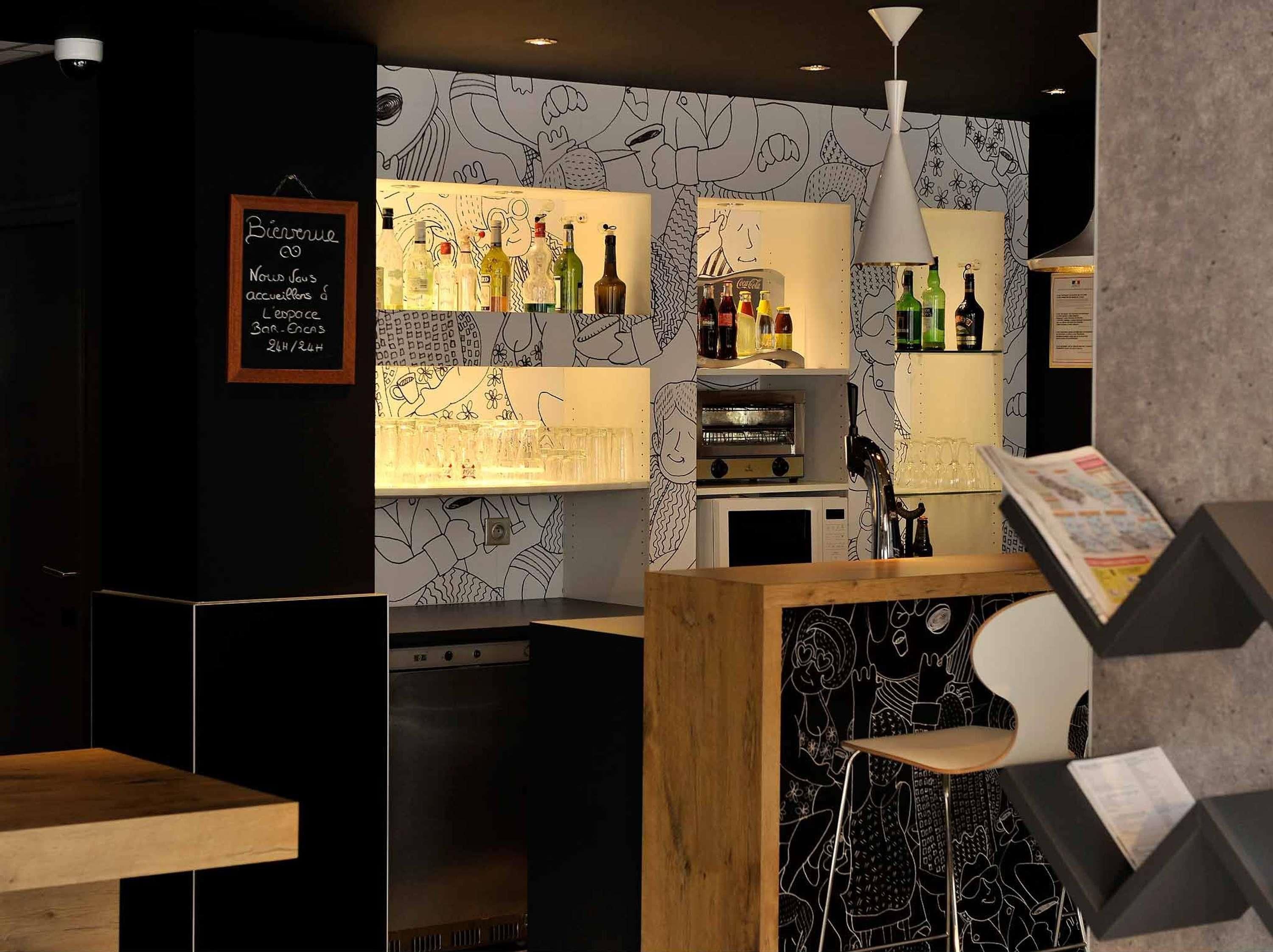 A bar area with a chalkboard menu, shelves of liquor bottles, a coffee machine, and a seating area with stools.
