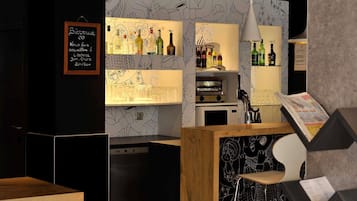 A bar area with a chalkboard menu, shelves of liquor bottles, a coffee machine, and a seating area with stools.