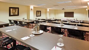 Un salón de conferencias con varias mesas, sillas y una pantalla para proyector.