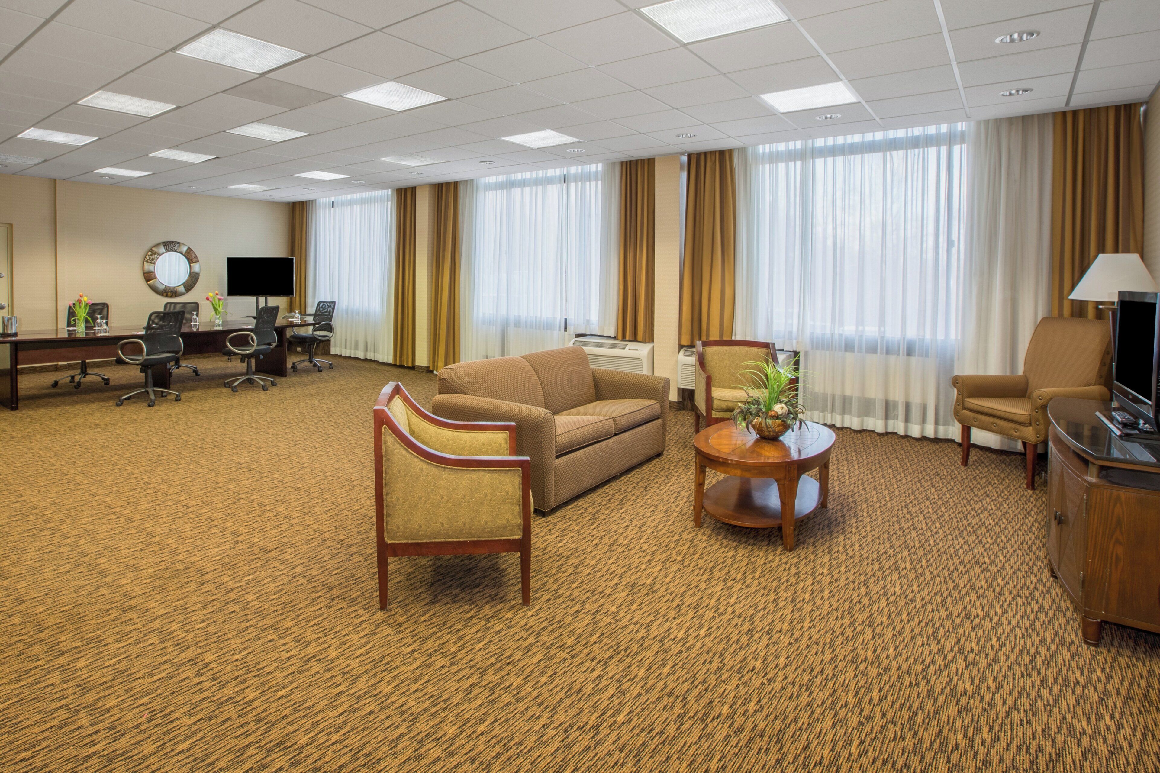 A hotel room with a large bed, a sofa, a coffee table, a TV, a desk, and a chair.