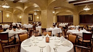 Un comedor elegante con mesas redondas, manteles blancos y centros de mesa con velas.