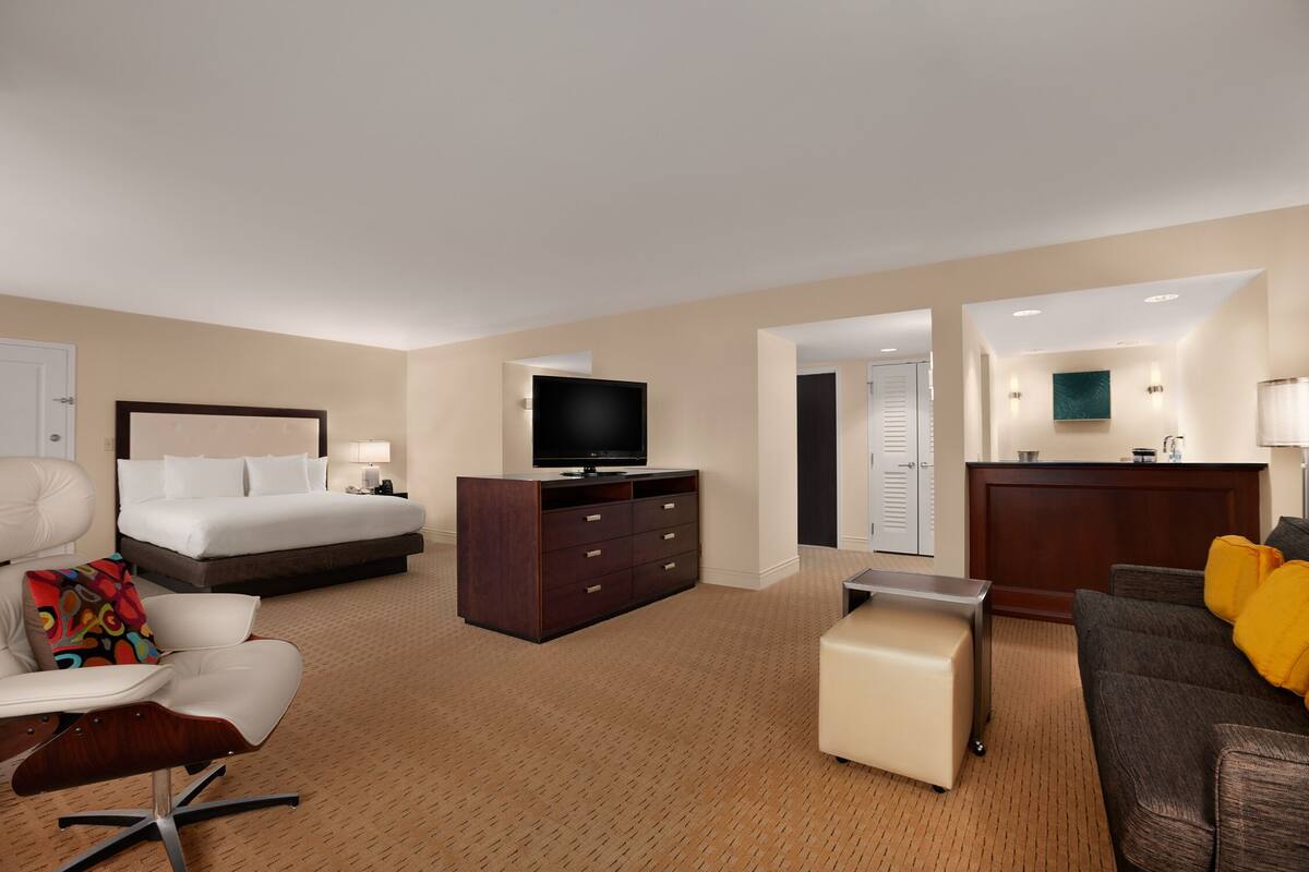 A hotel room with a bed, a TV, a desk, a chair, and a sofa.