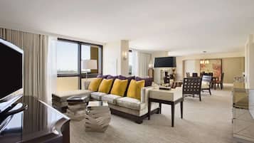 Ein modernes Hotelzimmer mit einer Couch, einem Fernseher und einem Essbereich.