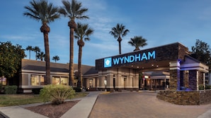 A Wyndham hotel with a modern facade, palm trees, and a well-lit entrance.