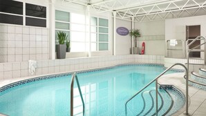 Une piscine intérieure à l’eau d’un bleu limpide, avec des murs carrelés et un poste de surveillance pour le sauveteur.