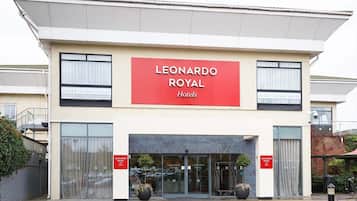 A hotel entrance with a prominent red sign reading 'LEONARDO ROYAL Hotels'.