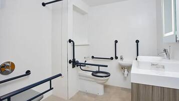 A modern bathroom with a white toilet, a sink, and a shower area.