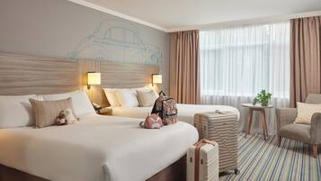 Two large beds with white linens and pillows, a small table, and a comfortable armchair.