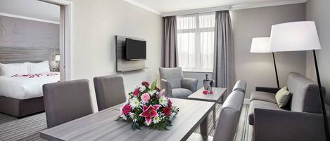 Hotelkamer met een bed, een televisie, een bureau met bloemen, een bank en een lamp.