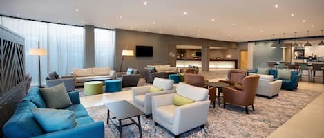 A spacious living area with multiple seating options, a kitchen in the background, and a modern design.