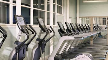 Varias bicicletas estáticas en un gimnasio con ventanas amplias y techo alto.